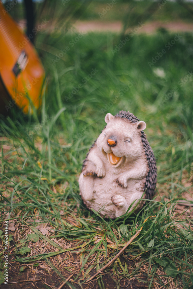 Obraz premium Close-up garden figurine decoration cheerful hedgehog on a blurred green background of grass and guitar