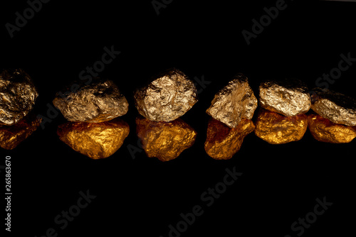 gold shiny stones in row with reflection isolated on black with copy space