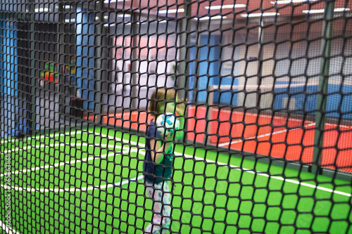 Blurred children are playing behind the net at indoor playground in activity park.