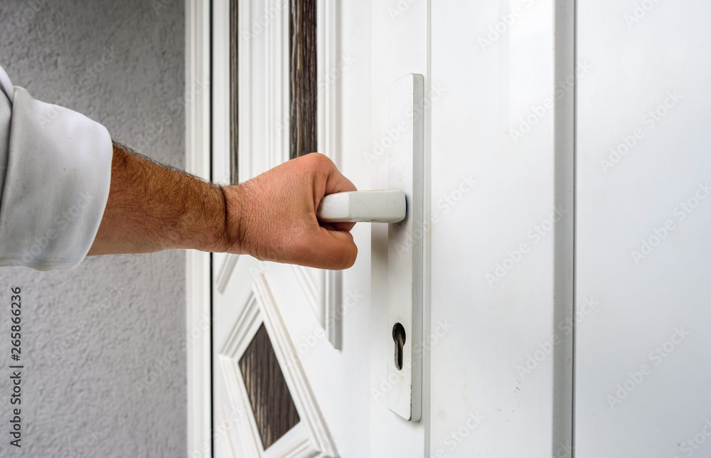 front door. hand holds doorknob on front door PVC front door. hand holds doorknob on front door PVC