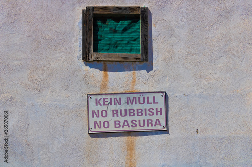 No rubbish sign in German, English and Spanish on the dirty wall - Image © Olena