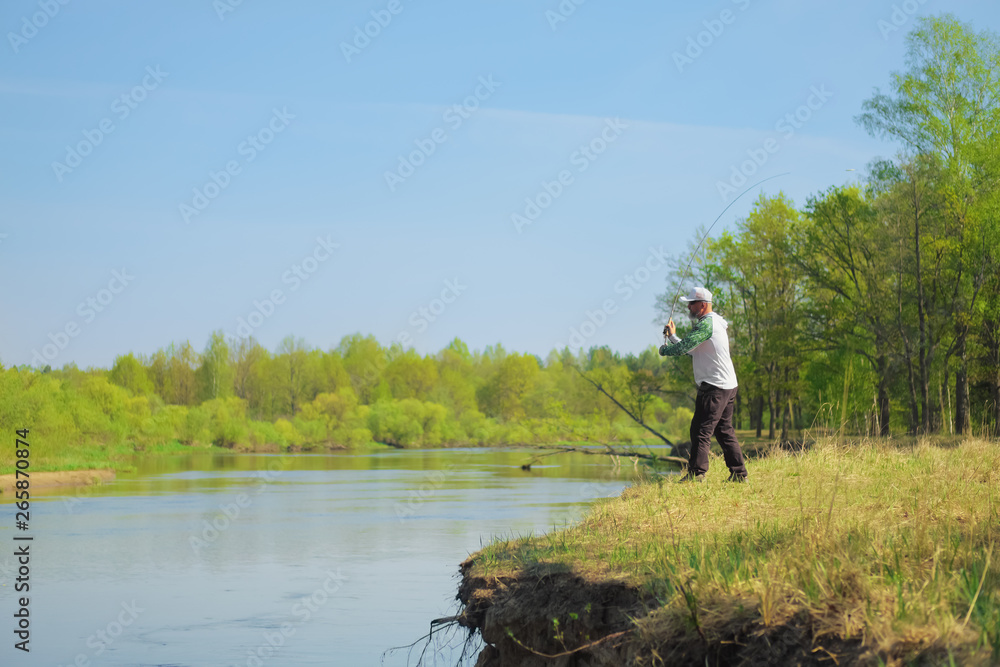 Fisherman throwing the bait with a spinning rod. Outdoor weekend activity. Photo with shallow depth of field taken at wide open aperture. Fisherman throwing the bait with a spinning rod. Outdoor weekend activity. Photo with shallow depth of field taken at wide open aperture.