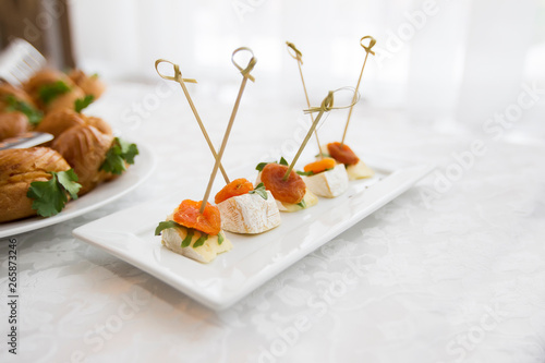Buffet dishes.Canapes on a white plate. Small sandwiches on a stick. Snack