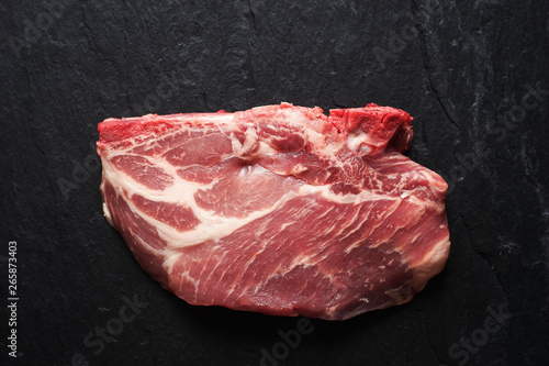 Fresh raw pork steak on black stone background top view space for text Close-up