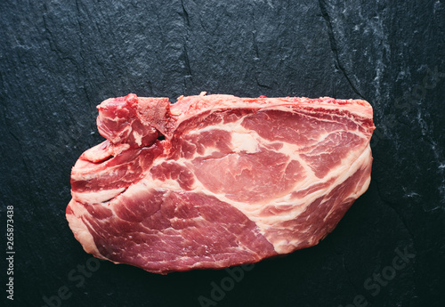 Fresh raw pork steak on black stone background top view space for text