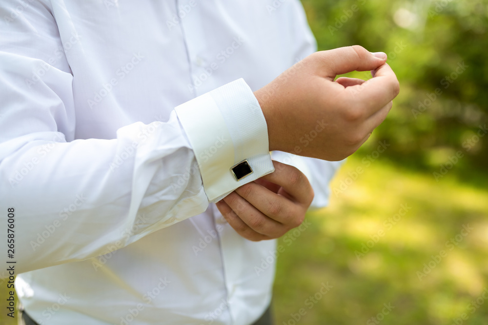 A man puts on an expensive shirt with cufflinks in the morning.