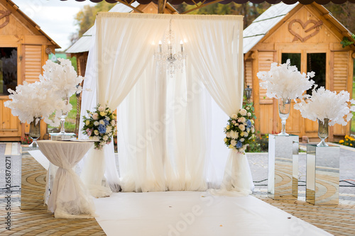 Arch for the wedding ceremony. Decorated with crystal chandelier and fresh flowers. Wedding decorations. The newlyweds.