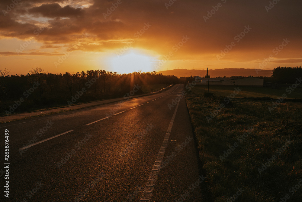 Misterious road during sunrise with a car going in the background.