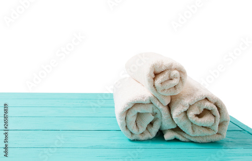 Rolled white towels on blue wooden table isolated on white background. Copy space and top view. Bathroom objects for shower body treatment. Selective focus. Banner