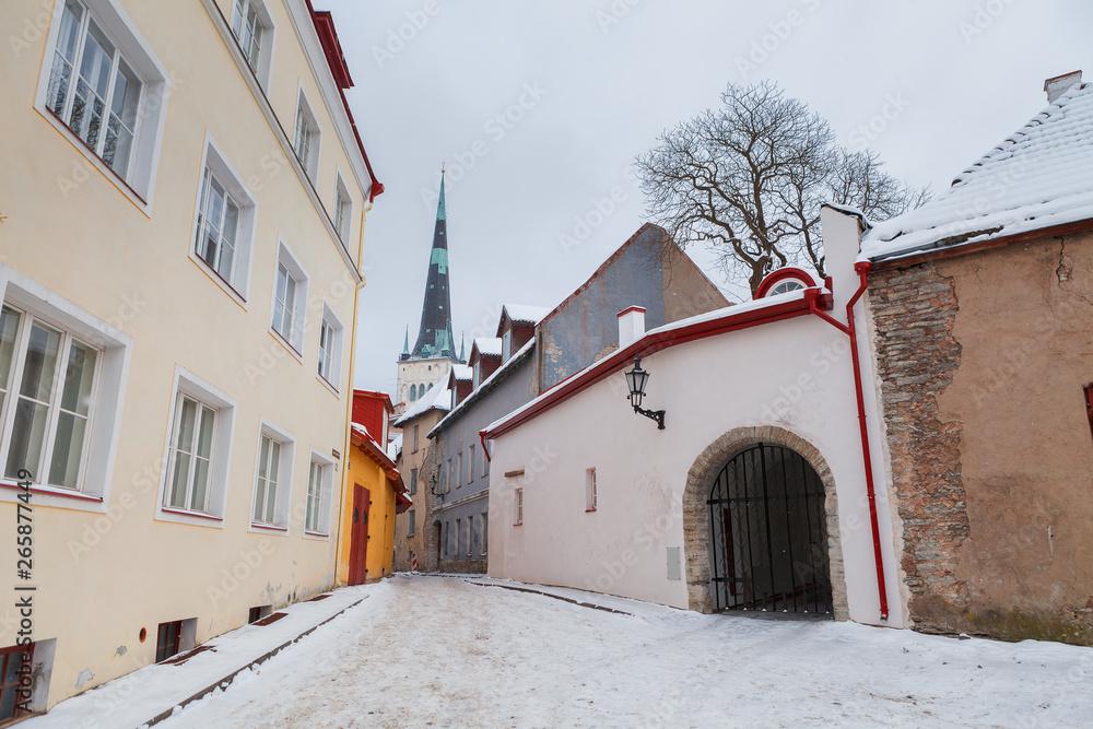 Streets of old Tallinn in winter. Oleviste church tower at the backgrond