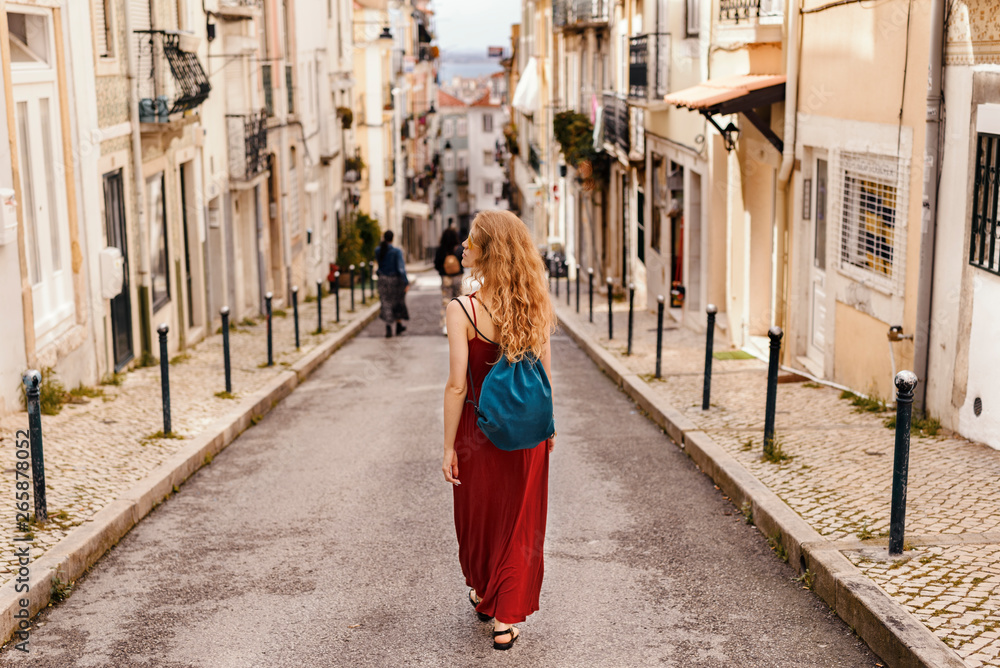 Woman in red dress exploring narrow streets of european city streets