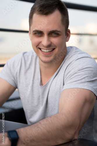 Young man connecting with a laptop at the cafe. Town buildings on background Free Download Young man connecting with a laptop at the cafe. Town buildings on background - GFXLoad