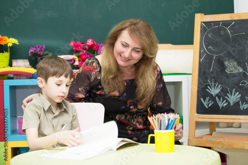 Teacher with a preschooler. Woman with a junior student in a bright children's room
