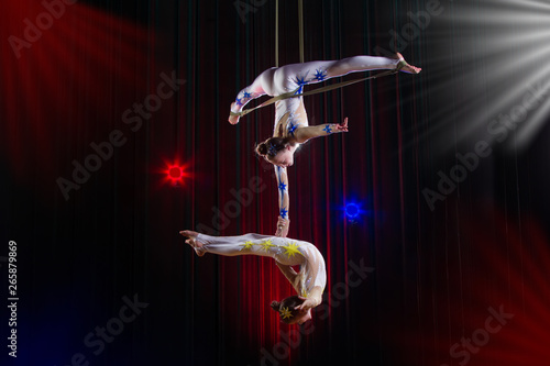 Circus actress acrobat performance. Two girls perform acrobatic elements in the air. photo