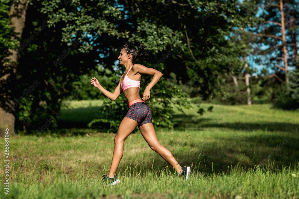 Young female runner jogging during outdoor workout in a park. Beautiful fit girl. Weight Loss. Sport LIfestyle.