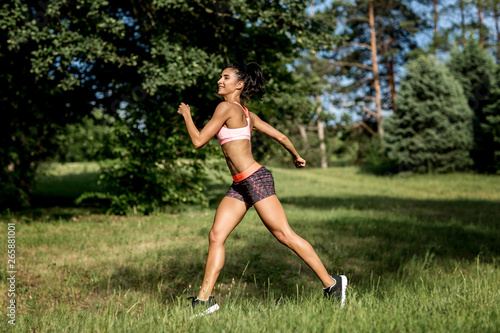 Young female runner jogging during outdoor workout in a park. Beautiful fit girl. Weight Loss. Sport LIfestyle.