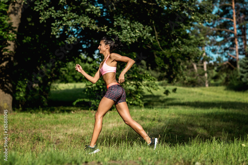 Young female runner jogging during outdoor workout in a park. Beautiful fit girl. Weight Loss. Sport LIfestyle.