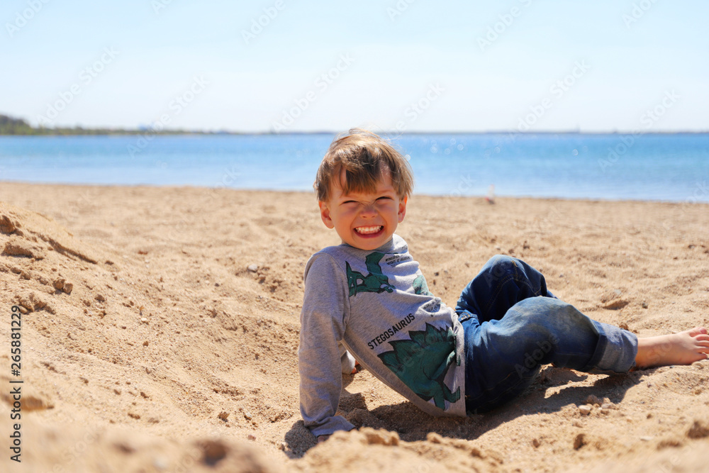 Ein dreijähriger Junge liegt im Sand Ein dreijähriger Junge liegt im Sand