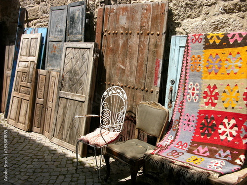 Schöne alte Holztüren und bunter Teppich als Antiquitäten im Sommer bei Sonnenschein in den Gassen der Altstadt von Alacati bei Cesme am Ägäischen Meer in der Provinz Izmir in der Türkei photo