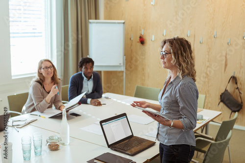 Confident businesswoman discussing with colleagues in meeting at office photo