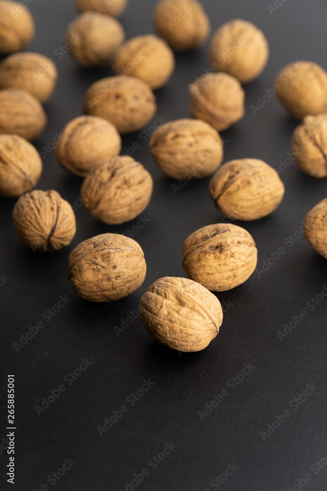 Walnuts in shell lying on black surface, side view. Healthy nuts and seeds background. Walnuts in shell lying on black surface, side view. Healthy nuts and seeds background.