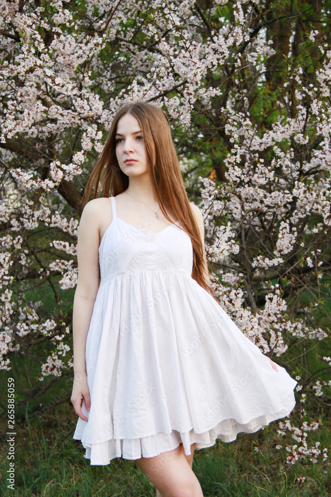 Beautiful young girl in white dress stay in sakura garden