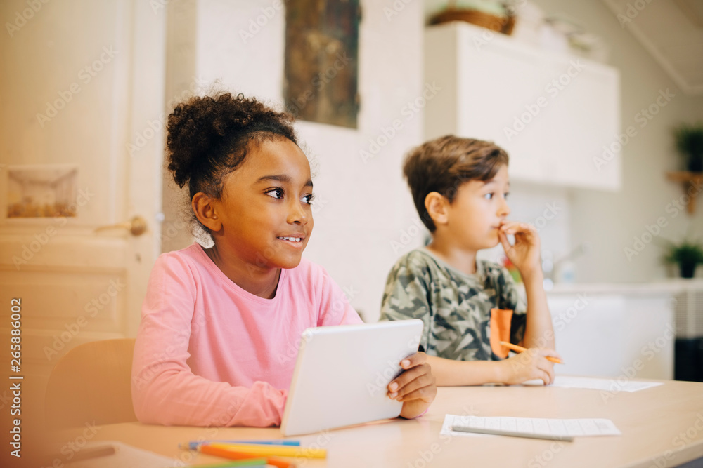 Boy learning through digital tablet while sitting with friend at classroom Boy learning through digital tablet while sitting with friend at classroom