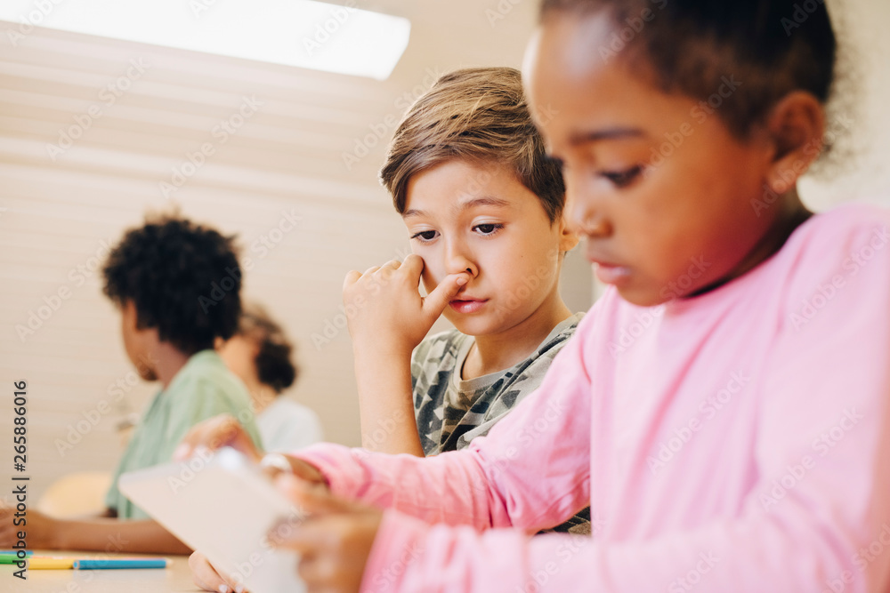 Boys using digital tablet while learning at classroom Boys using digital tablet while learning at classroom