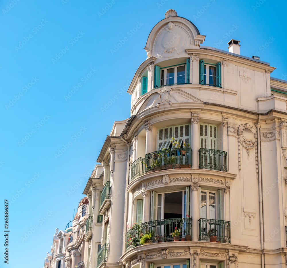 View to the decorated facade of a historic house in Nice, France. You can see the typical windows, balconies and shutters of a Mediterranean cityscape.
