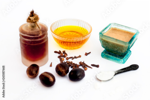 Best exfoliator isolated on white i.e. Nutmeg powder well mixed with clove oil and some honey and baking soda in a glass bowl along with Raw baking soda,honey,clove oil and nutmeg present. photo