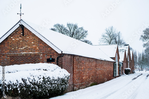 Exterior view of red brick cottages with snow-covered roofs along a rural road.,Aston Rowant photo