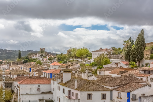 View of the fortress and Luso Roman castle of Óbidos, with buildings of Portuguese vernacular architecture and sky with clouds, in Portugal