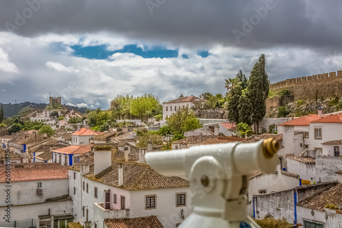 View of the fortress and Luso Roman castle of Óbidos, with buildings of Portuguese vernacular architecture and sky with clouds, blurred monocle on first plan, in Portugal photo