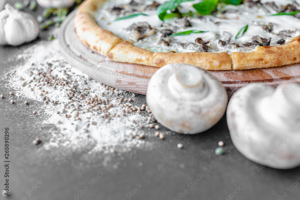 Champignons and pizza with zucchini on the wooden plate, flour and spices near. Horizontal image. Natural light. Black background. Shallow focus. Champignons and pizza with zucchini on the wooden plate, flour and spices near. Horizontal image. Natural light. Black background. Shallow focus.