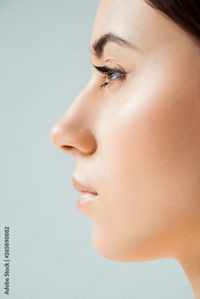 profile of young woman with shiny lips, highlighter and golden eye shadow isolated on grey profile of young woman with shiny lips, highlighter and golden eye shadow isolated on grey