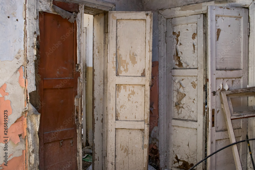 Doors to the room of an old abandoned house with peeling white paint