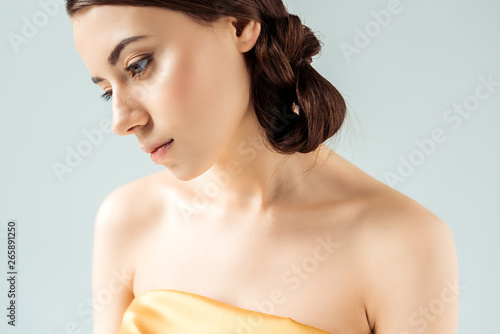 young woman with shiny lips and golden eye shadow isolated on grey