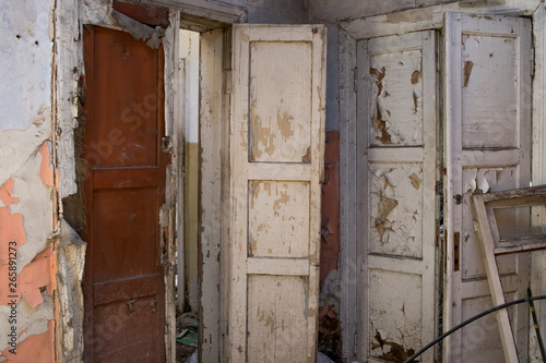 Doors to the room of an old abandoned house with peeling white paint © Татьяна Грунт