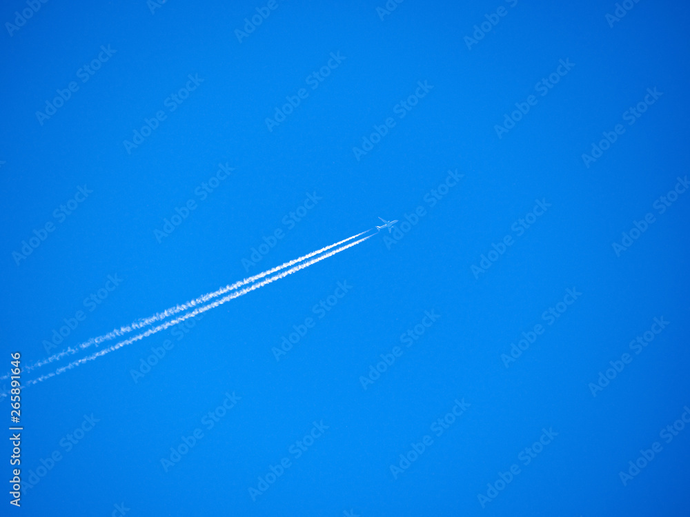 Traces of exhaust gases from the aircraft engine. White stripes and a plane on a bright blue sky. Modern jet plane with white condensation track. Travel concept. Beautiful background or wallpaper. Traces of exhaust gases from the aircraft engine. White stripes and a plane on a bright blue sky. Modern jet plane with white condensation track. Travel concept. Beautiful background or wallpaper.