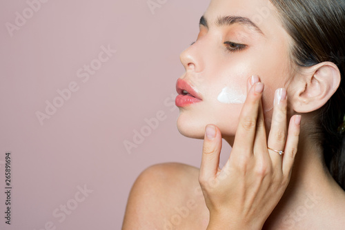 Skin cream concept. Facial care for female. Keep skin hydrated regularly moisturizing cream. Fresh healthy skin concept. Taking good care of her skin. Beautiful woman spreading cream on her face