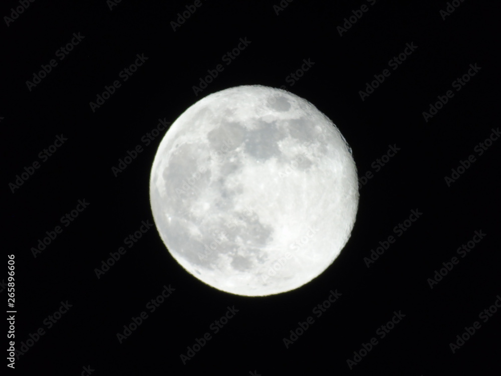 Genova, Italy - 03/22/2019: An amazing photography of the full moon over the city of Genova by night with a great clear sky in background and some stars