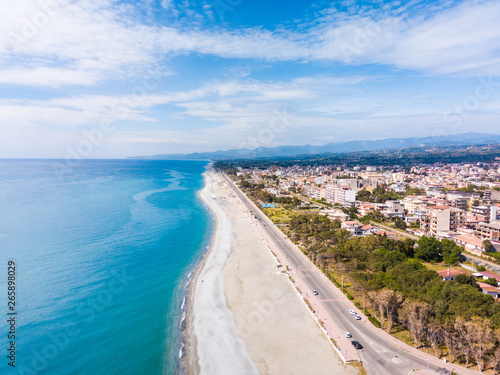 Panoramica aerea del lungomare di Locri, in Calabria. La spiaggia bianca, il mare Mediterraneo blu e le case della città.