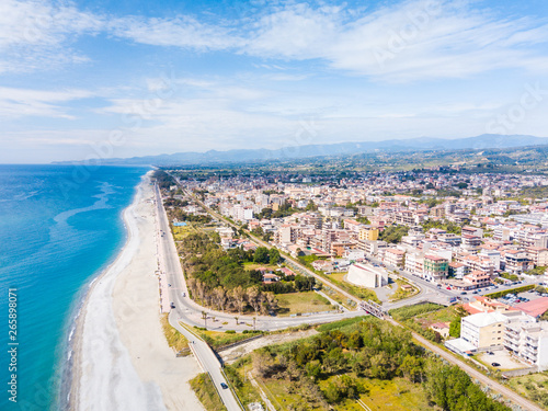 Panoramica aerea del lungomare di Locri, in Calabria. La spiaggia bianca, il mare Mediterraneo blu e le case della città.