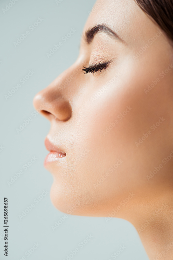 profile of young woman with closed eyes, shiny lips and golden eye shadow isolated on grey profile of young woman with closed eyes, shiny lips and golden eye shadow isolated on grey