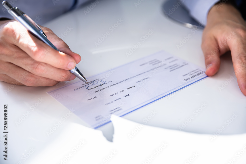 Close-up Of Hand Filling Cheque Close-up Of Hand Filling Cheque