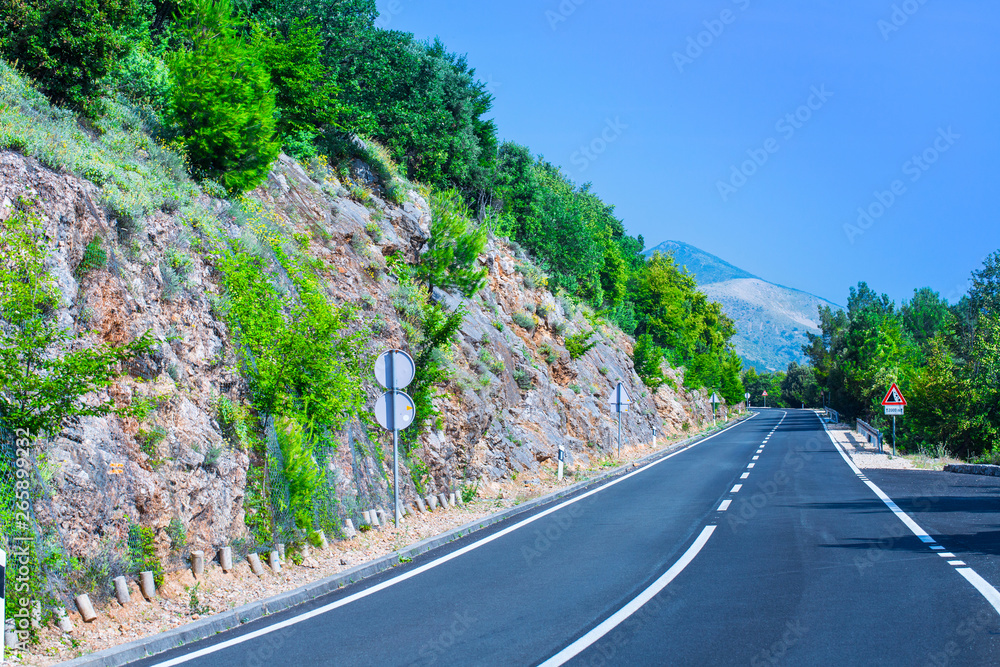 Beautiful asphalt freeway, motorway, highway without traffic in southern mountains forest landscape. Summer sunny weather. Travel road concept. Island Cres in the Adriatic Sea. Croatia.