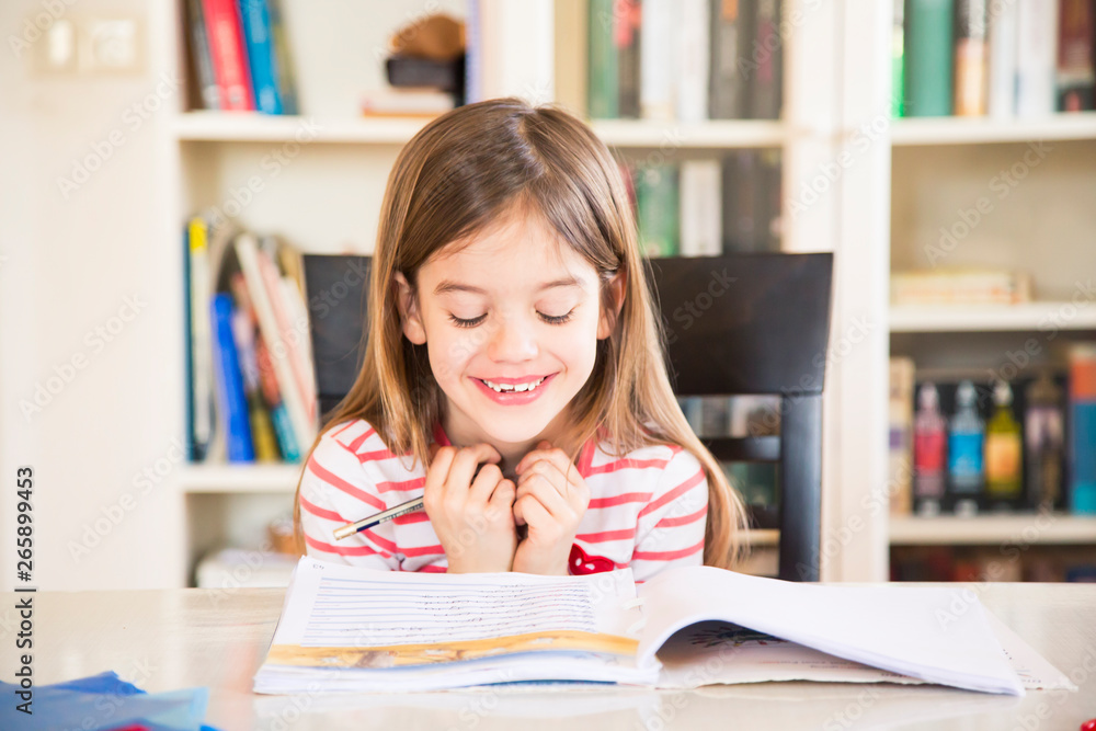 Portrait of happy little girl doing homework