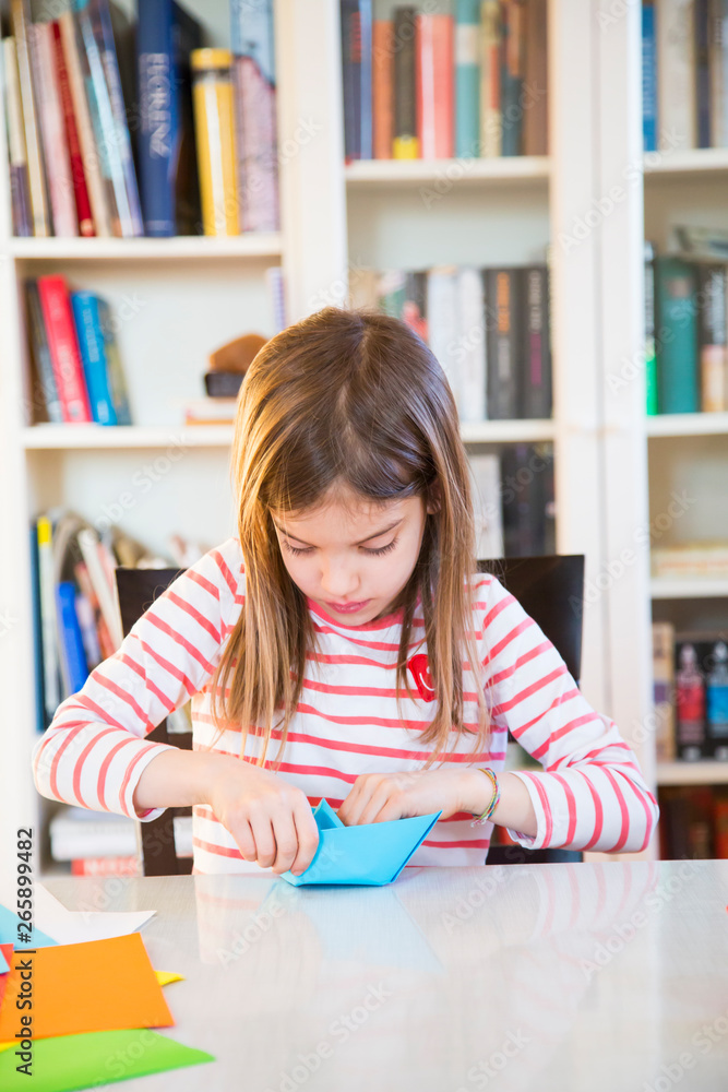 Girl tinkering with paper on table at home Girl tinkering with paper on table at home