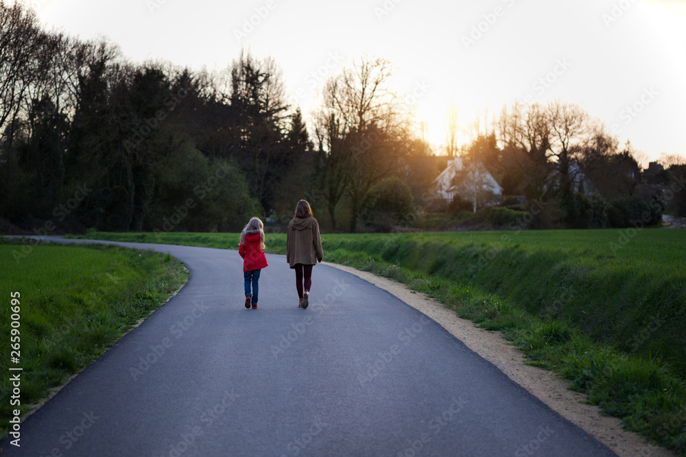 Fototapeta premium the sisters go along the empty road in the evening