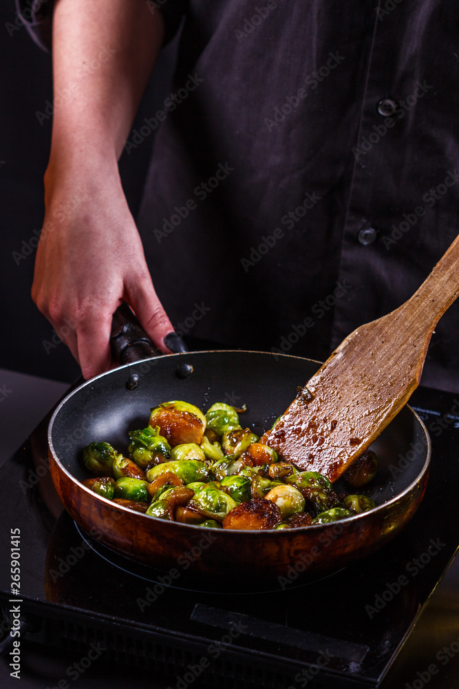 young woman fries Brussels sprouts on a frying pan young woman fries Brussels sprouts on a frying pan
